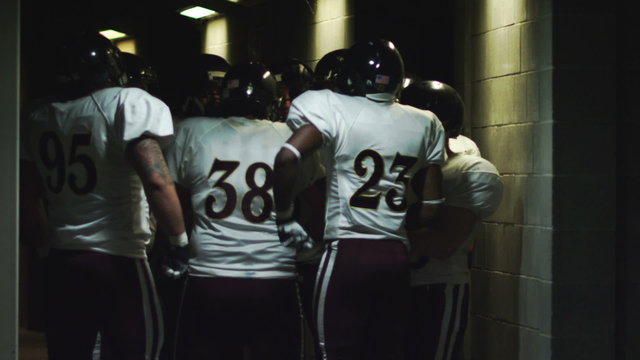 A football team in a circle gets pumped-up in the tunnel before the game