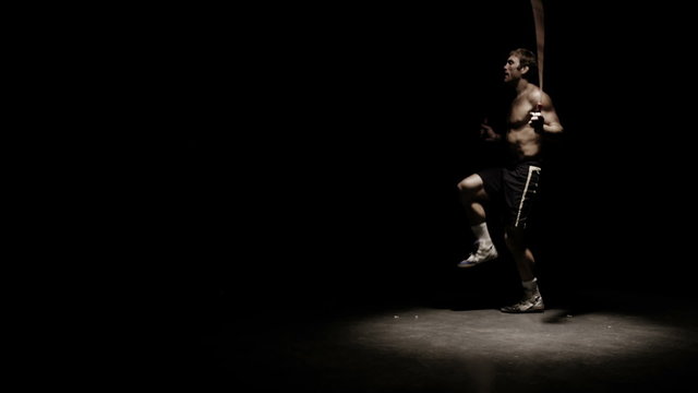 Athlete does fitness training by jumping rope. Medium shot.