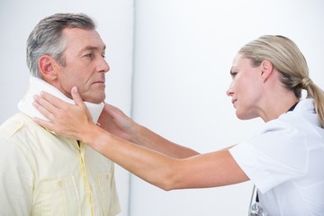 Obraz premium Doctor examining patient wearing neck brace