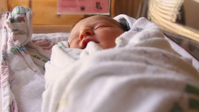 A newborn baby sleeping in the hospital crib after being born