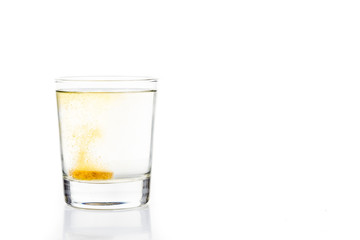 Effervescent vitamin C tablet bubbles in glass of water