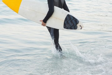 Man in wetsuit with a surfboard on a sunny day