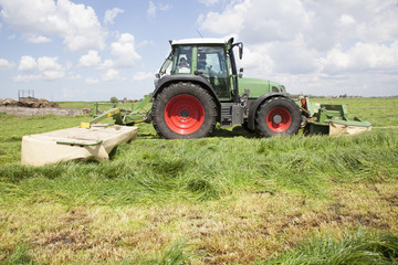 tractor and mower in green meadow