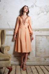 Fototapeta premium Vintage portrait of a beautiful girl standing next to the chair