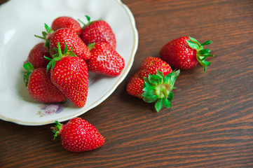 Strawberries on a plate on wooden background