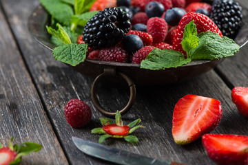 Fresh summer berries with mint in rustic bowl