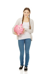 Teenage woman holding piggybank.