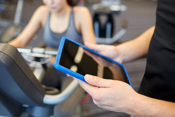 close up of trainer hands with tablet pc in gym