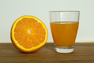 Glas frisch gepresster Orangensaft neben einer Orangenhälfte