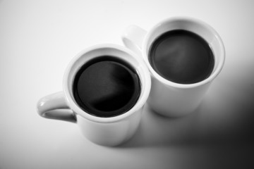 Two cups full of coffee stand on a table