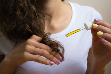 Young girl caring for curly hair tips using a  oil © progressman