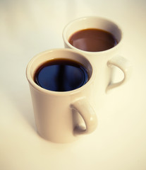 Two cups full of coffee stand on the table