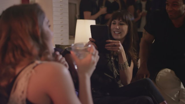 Group of young adults play around with a tablet together while at a house party