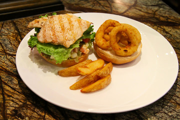 Delicious steak burger served with onion rings and fries.