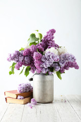Beautiful lilac in watering can on white wooden background