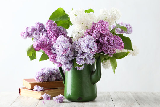 Beautiful lilac in pitcher on white wooden background