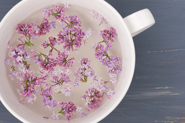 Fresh lilac flower petals floating in the white ceramic bowl.