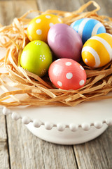 Fototapeta na wymiar Easter eggs in nest on grey wooden background