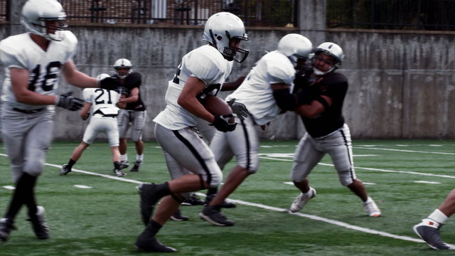 A Running Back receives a handoff and sidesteps and spins past defenders