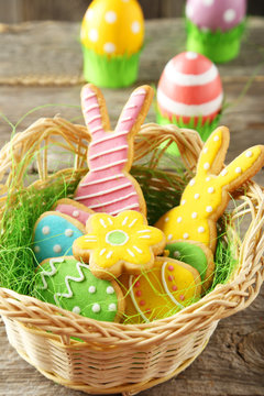 Colorful easter cookies in basket on grey wooden background