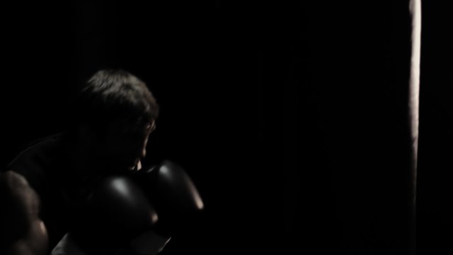 Boxer works on his power by hitting a punching bag. Medium shot.