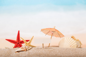 Fototapeta na wymiar Umbrella, shells and starfishes in sand