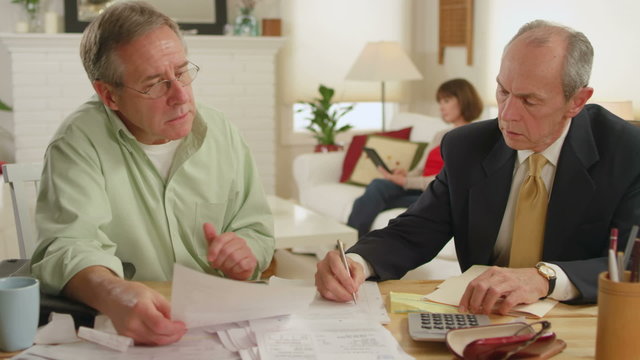 A senior adult gets help with his bills by a professional adviser