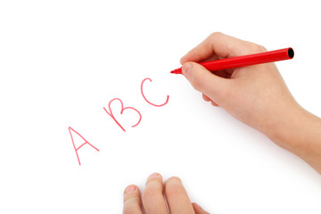 Childs hands writing letters on white paper