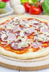 Pizza dough with salami, bacon, mushrooms and cheese