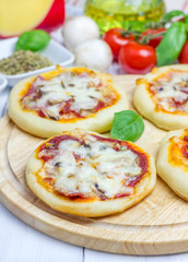 Mini pizza with salami, bacon, mushrooms and cheese