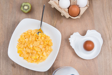 Cornflakes with milk, eggs,  on a wooden brown background
