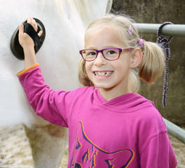 Mädchen striegelt Pferd mit Bürste © Dan Race