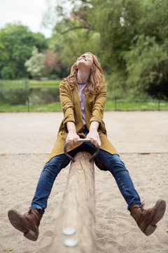 lachende junge frau auf einer wippe im park