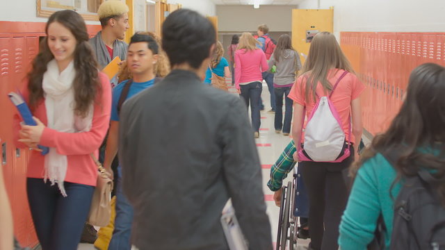 A school hallway clears out as students rush to get into their classrooms