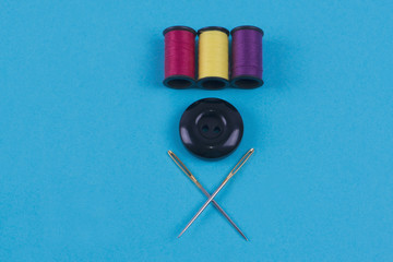 Button with needle and thread colors on a blue background