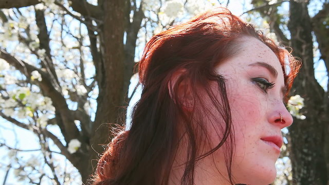 Beautiful Redhead by a tree in a park