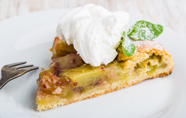 Piece of sweet cake with rhubarb and whipped cream