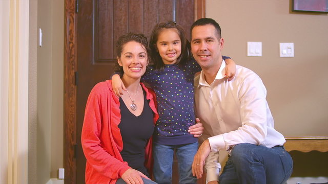 A girl puts her arms around her mom and dad before going to work and school