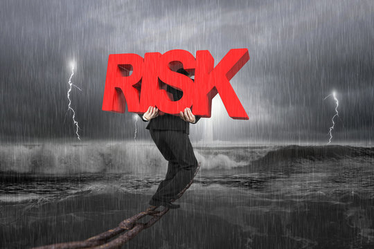 Man carrying red RISK word on chain with stormy ocean