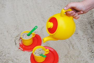 Teekanne und Tassen in einem Sandkasten