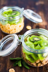 Wheat and corn flakes with yogurt and kiwi in the jar