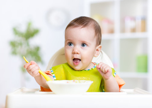 happy baby kid eating food itself with spoon