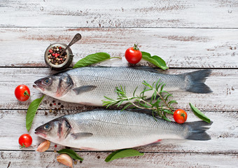 Two raw seabass with spices on an old wooden background