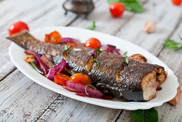 Roasted seabass with vegetables on an old wooden background