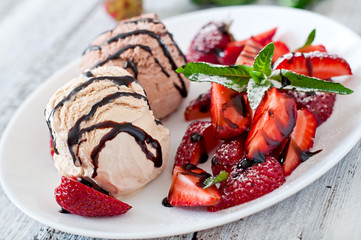 Ice cream with strawberries and chocolate on a white plate