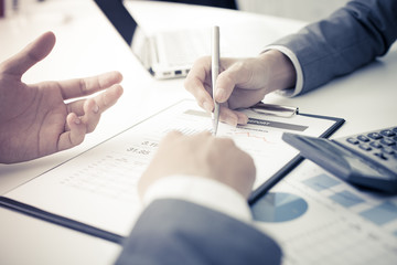 Two businessmen looking at report and having a discussion in off