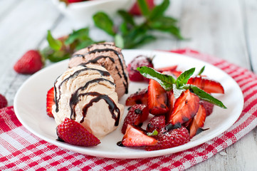 Ice cream with strawberries and chocolate on a white plate