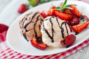 Ice cream with strawberries and chocolate on a white plate