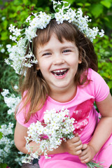 Funny little girl in a wreath playing on the lawn