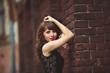 Fototapeta premium beautiful sexy brunette woman standing near a brick wall in dres